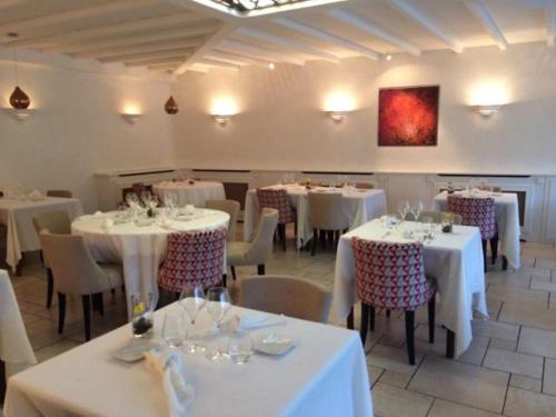 uma sala de jantar com mesas e cadeiras brancas em Logis Hotel Restaurant Le Bellevue em Prats-de-Mollo-la-Preste