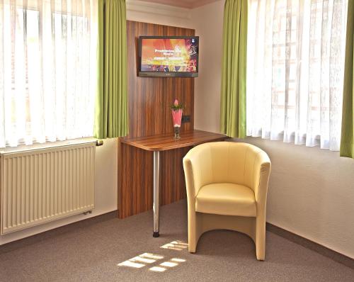 a room with a table and a chair and a television at Hotel Garni Goldene Traube in Bad Windsheim