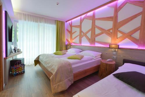 a bedroom with two beds with purple lights on it at Aktivhotel Santalucia in Nago-Torbole
