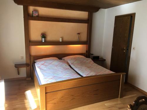 Schlafzimmer mit einem Bett mit einem Kopfteil aus Holz in der Unterkunft Pension Thilo in Bad Wildbad
