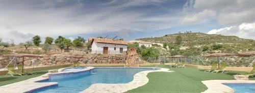 a swimming pool in a resort with a mountain at Complejo Rural El Molinillo in Arenas del Rey