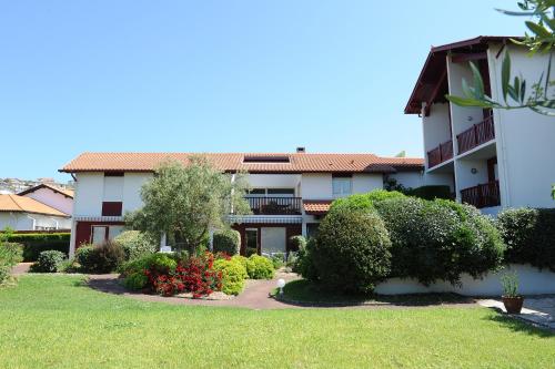 a building with a yard with bushes and trees at Hotel & Appartements Gochoki in Bidart