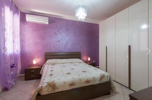 1 dormitorio con paredes moradas y 1 cama con 2 lámparas en Casa Vacanze Rosalba en Vignacastrisi