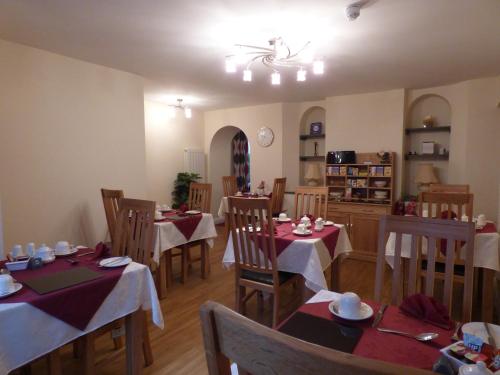 uma sala de jantar com mesas e cadeiras com guardanapos vermelhos em The Paddock Guest House em Keswick