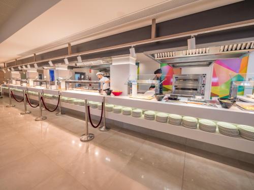 een keuken met mensen die eten bereiden in een restaurant bij Golden Taurus Aquapark Resort in Pineda de Mar