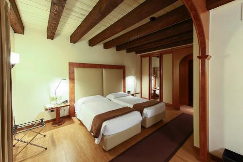 a bedroom with two beds in a room with wooden ceilings at Relais Villabella Hotel in San Bonifacio