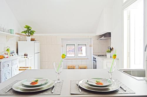 a white kitchen with a table with plates and glasses at Belém Apartment in Lisbon