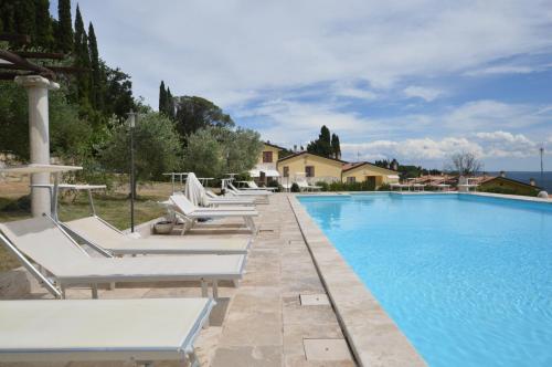 - une piscine bordée de chaises longues blanches dans l'établissement Villa Le Querciolaie, à Monteverdi Marittimo