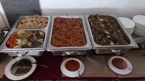 a buffet with four trays of different types of food at Hotel LAFORGE in Abidjan