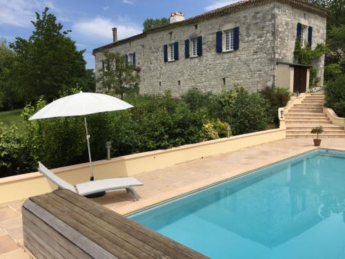 un parasol et une chaise à côté de la piscine dans l'établissement Bergerie Le Vieux Manoir, à Valeilles