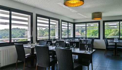 een eetkamer met tafels, stoelen en ramen bij Hôtel Restaurant Aldaburua in Larressore