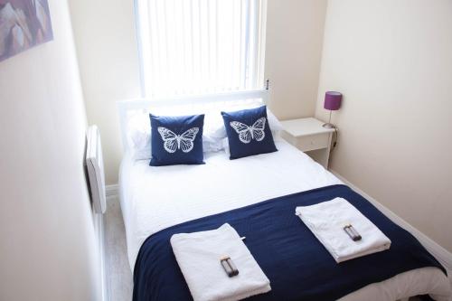 a bedroom with a bed with blue pillows with butterflies on it at East Village City Center Luxury Apartment in Liverpool