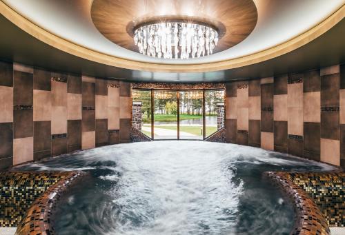 a hot tub in a room with a chandelier at Sala Resort Plateliai & SPA in Plateliai