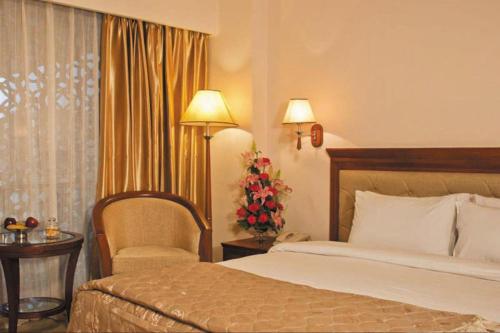 a hotel room with a bed and a chair at Clarion Bella Casa at Airport in Jaipur