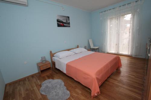 a bedroom with a bed with a orange blanket and a window at Apartman Seaside Paradise in Split
