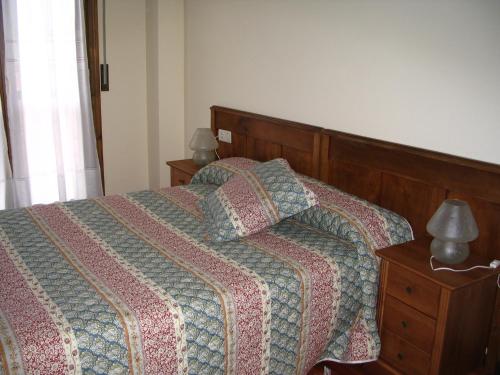 een slaapkamer met een bed met een quilt en 2 lampen bij Pension Txomin Ostatua in Etxebarria