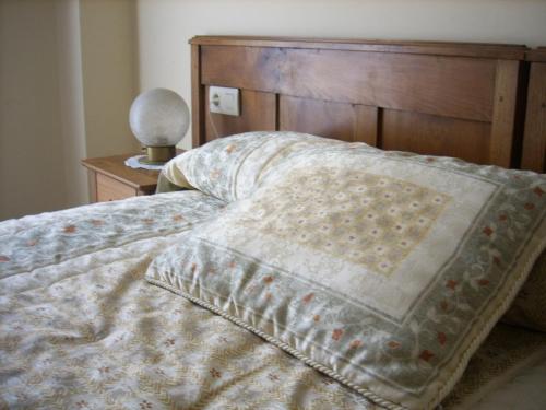 a bed with a comforter and a wooden head board at Pension Txomin Ostatua in Etxebarria