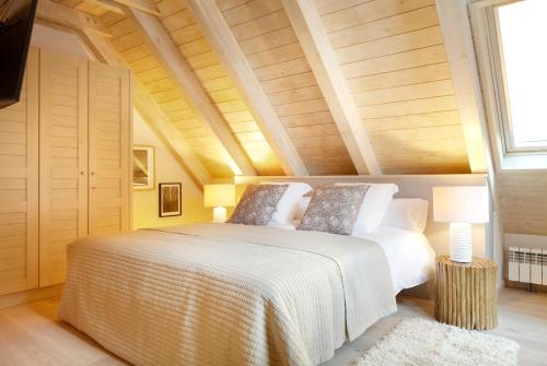 - une chambre avec un lit blanc et un plafond en bois dans l'établissement Val de Ruda Luxe 50 by FeelFree Rentals, à Baqueira-Beret