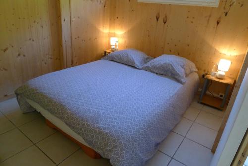 a bedroom with a bed with two lamps on two tables at CHALET 407 KHELUS-CLUB in Gujan-Mestras