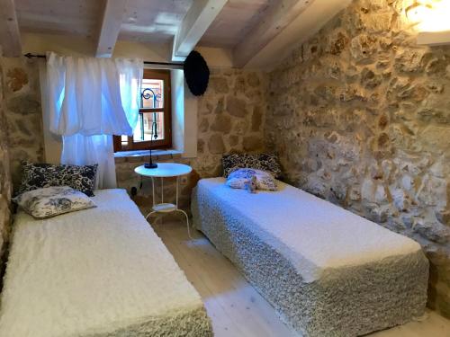 two beds in a room with a stone wall at Holiday Homes Susak Sansego in Susak