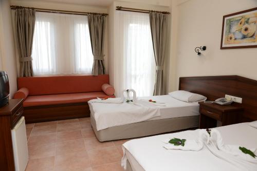 Habitación de hotel con 2 camas y sofá en Karbel Beach Hotel en Oludeniz