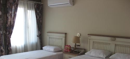 a bedroom with two beds and a window at Assos Sunaba Kasri Hotel in Behramkale
