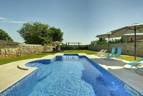 uma piscina com duas cadeiras e um guarda-sol em Villa Orbanici em Barban