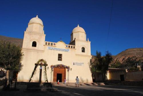a white church with a man standing in front of it at Alojamiento El Cardon Tilcara in Tilcara