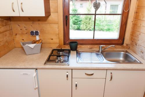 a kitchen with a sink and a stove and a window at Adria Domki in Pobierowo