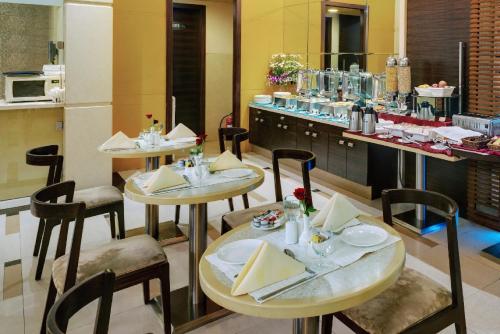 ein Restaurant mit zwei Tischen und Stühlen und einer Theke in der Unterkunft Grand Residency Hotel & Serviced Apartments in Mumbai
