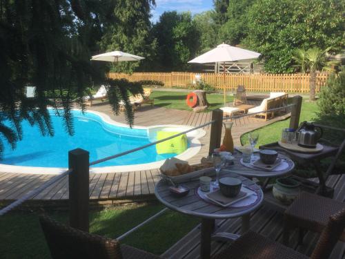 Una piscina con mesas y sombrillas en un patio trasero. en Les Crinieres En Brie, en Saint-Ouen-en-Brie