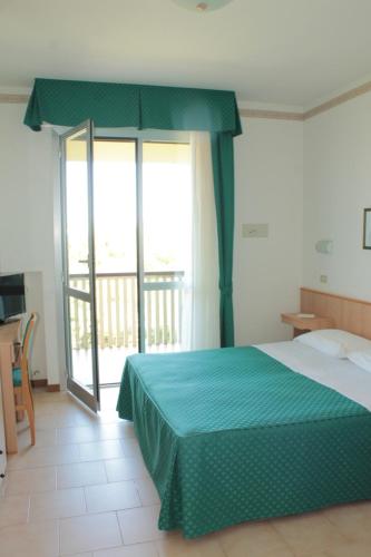 a bedroom with a bed with a green bedspread at Hotel Fabiola in Giulianova