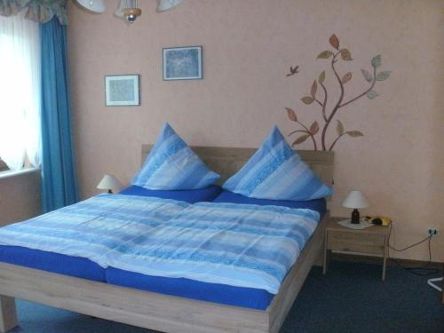 Gästehaus Ruth Andrae في بروتيج-فانكيل: غرفة نوم بسرير ازرق مع مخدات زرقاء