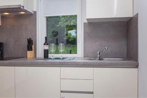 a kitchen with white cabinets and a sink and two wine glasses at Villa Eden in Labin