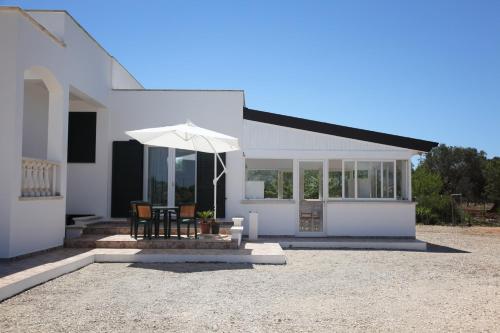 a white house with a table and an umbrella at Villa Giulia&Gaia - Guest House in Nardò