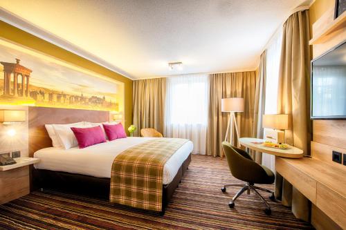 a hotel room with a large bed and a television at Leonardo Royal Edinburgh Haymarket in Edinburgh