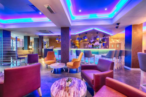 a restaurant with purple and orange chairs and a bar at Leonardo Hotel Edinburgh Haymarket in Edinburgh
