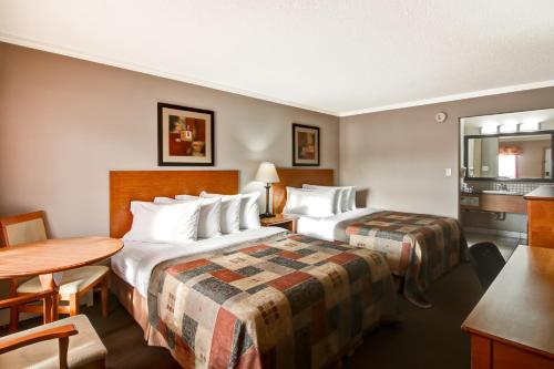 um quarto de hotel com duas camas e uma mesa em Canalta Stettler em Stettler