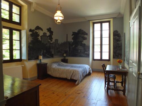 een slaapkamer met een bed en een tafel en ramen bij Chateau du Donjon in Drumettaz-Clarafond