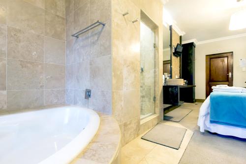 baño grande con bañera y lavamanos en OR Tambo Guest House, en Kempton Park