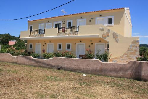 a large house behind a stone wall at Kosmos Hotel in Agios Stefanos