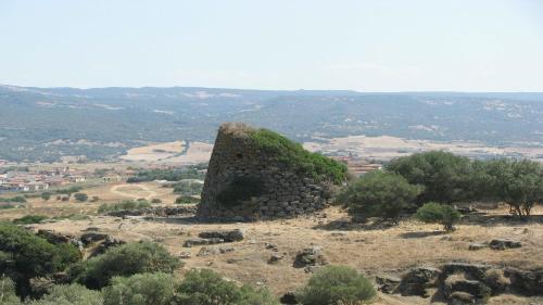 a stone tower on top of a hill with trees at B&B Pani Silvio in Perfugas