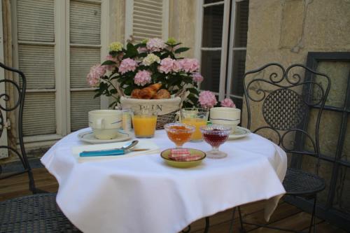 una mesa con un mantel blanco y un tazón de flores en Une Chambre en Ville en Saintes