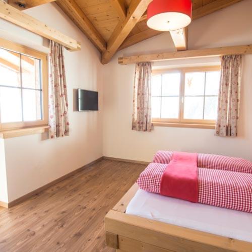 a bedroom with a bed with a red blanket on it at Herzl Hof in Zellberg