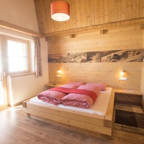 a bedroom with a bed with two pink pillows on it at Herzl Hof in Zellberg