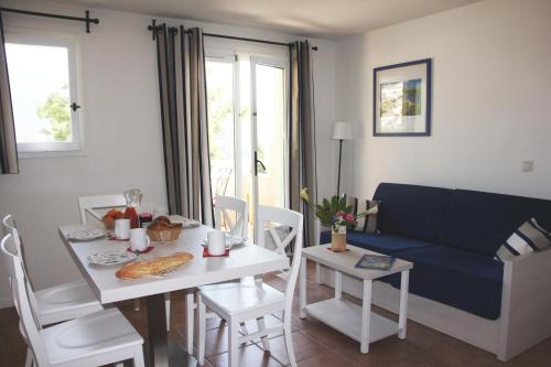 uma sala de estar com uma mesa e um sofá azul em Résidence Goélia Le Domaine de la Pinède em Le Lavandou