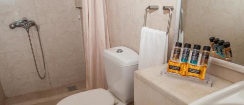 uma casa de banho com um chuveiro, um WC e um lavatório. em Hotel Saron em Poros