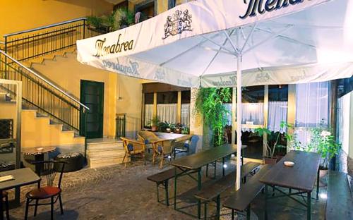 クルゾーネにあるAlbergo della Postaのテーブルと椅子、傘が備わるレストラン
