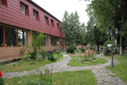 a garden in front of a red building at Туристично розважальний комплекс "Стіжок" in Berehomet