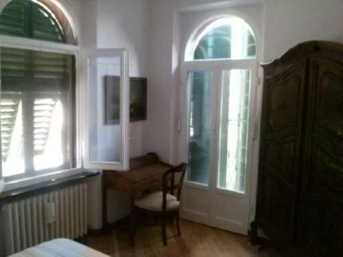 a bedroom with a chair and a desk and two windows at D'AGO48 in Ancona